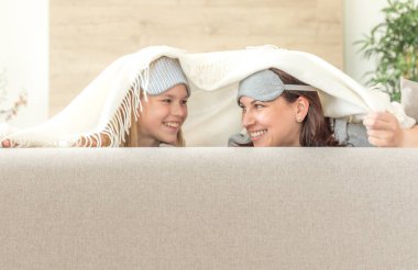 Anne ve kızı kopya alanı ile kanepede eğlenmek uyku maskesi giyiyor