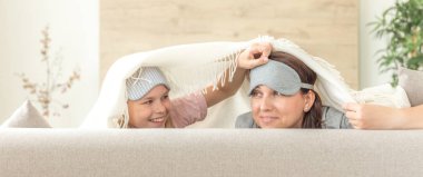 Anne ve kızı kopya alanı ile kanepede eğlenmek uyku maskesi giyiyor