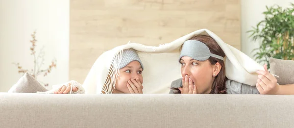 コピースペース付きソファで楽しむ睡眠マスクを着用した母と娘 — ストック写真