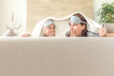 Anne ve kızı happ aile kavramı. uyku maskesi takmak ve oturma odasında kanepede eğlenmek