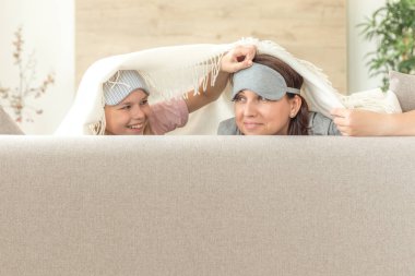 Anne ve kızı happ aile kavramı. uyku maskesi takmak ve oturma odasında kanepede eğlenmek