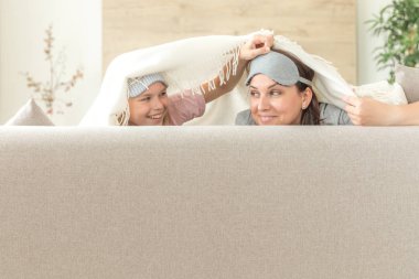 Anne ve kızı happ aile kavramı. uyku maskesi takmak ve oturma odasında kanepede eğlenmek