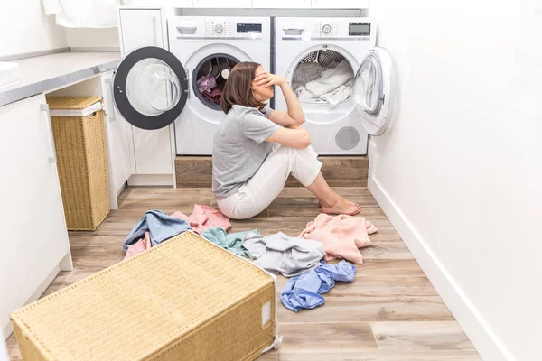 Young Tired sad Woman sitting on the floor in laundry room, back view — Stock Photo, Image