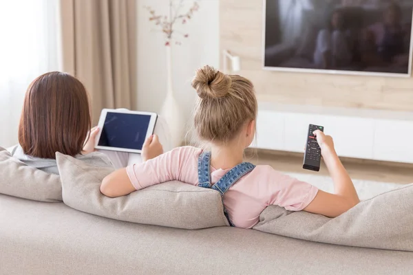 Anne ve kızı oturma odasında TV izlerken kanepede oturuyor — Stok fotoğraf
