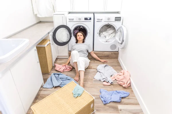 Щаслива жінка домогосподарка в пральні біля пральної машинки з брудним одягом — стокове фото