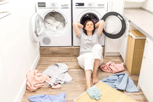 Boldog asszony háziasszony a mosodában közelében a piszkos ruhák mosógép — Stock Fotó