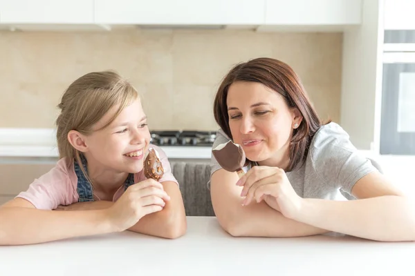 Mãe com sua filha de 12 anos sentada na cozinha comendo sorvete. Boas relações de pai e filho. Momentos felizes juntos — Fotografia de Stock