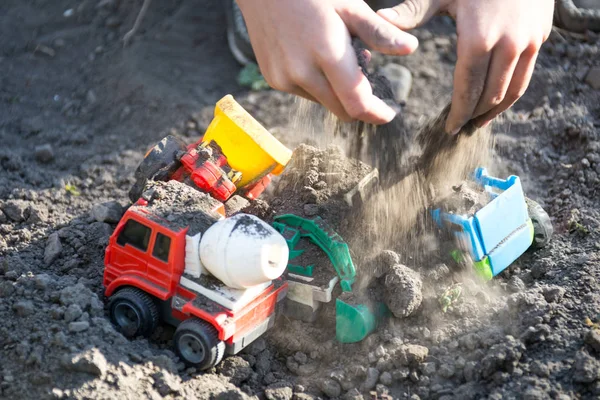 Kid brincando com tratores de brinquedo de plástico no quintal — Fotografia de Stock
