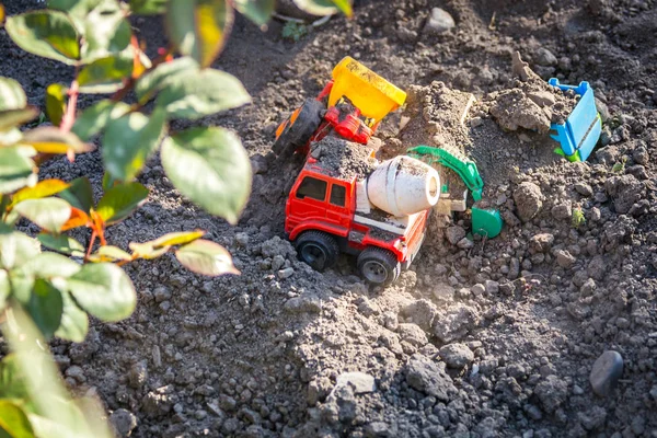 Bambino che gioca con trattori giocattolo di plastica in cortile — Foto Stock