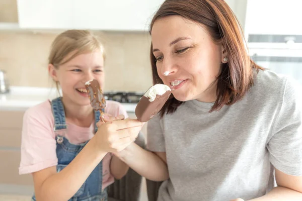Мать с дочерью на кухне едят мороженое. Хорошие отношения родителей и детей. Концепция счастливой семьи — стоковое фото