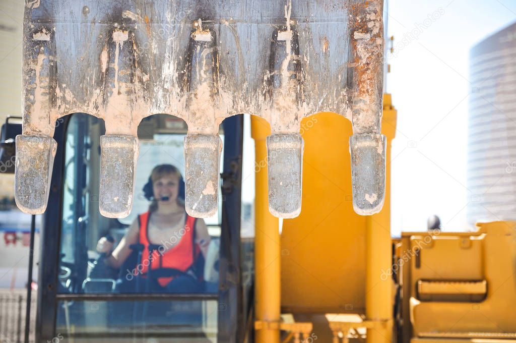 Woman in reflective clothing operating heavy excavator equipment