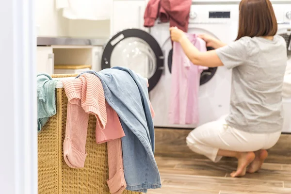 Жінка завантаження брудного одягу в пральній машині для прання в сучасному приміщенні — стокове фото
