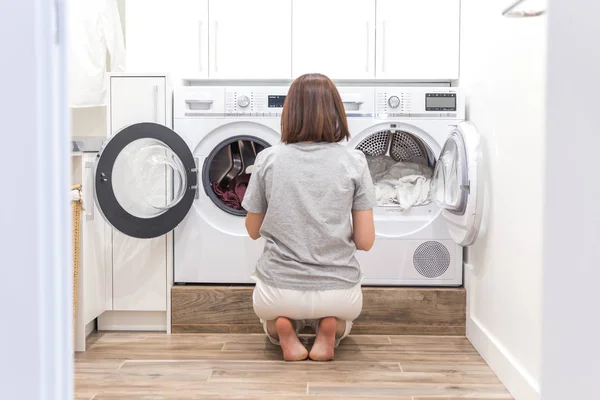 Mujer cargando ropa sucia en la lavadora para lavar en el cuarto de servicio moderno — Foto de Stock