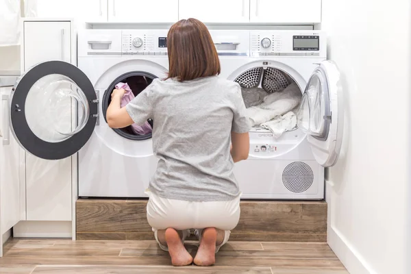 Mujer cargando ropa sucia en la lavadora para lavar en el cuarto de servicio moderno — Foto de Stock