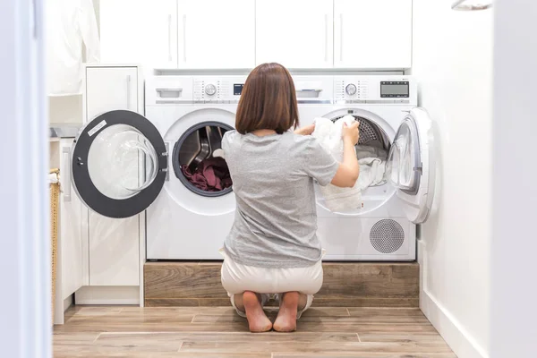Mulher carregando roupas sujas na máquina de lavar roupa para lavar na moderna sala de serviço público — Fotografia de Stock