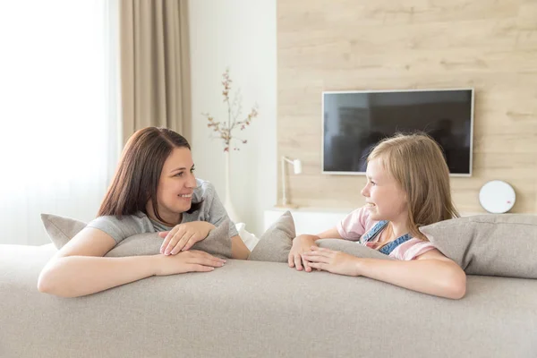 Mãe e filha pré-adolescente sentadas no sofá sorrindo. Conceito de família feliz — Fotografia de Stock