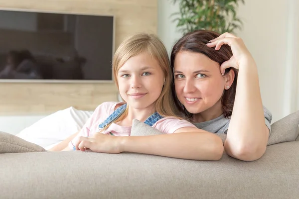 母亲和十几岁的女儿坐在沙发上微笑。幸福家庭理念 — 图库照片