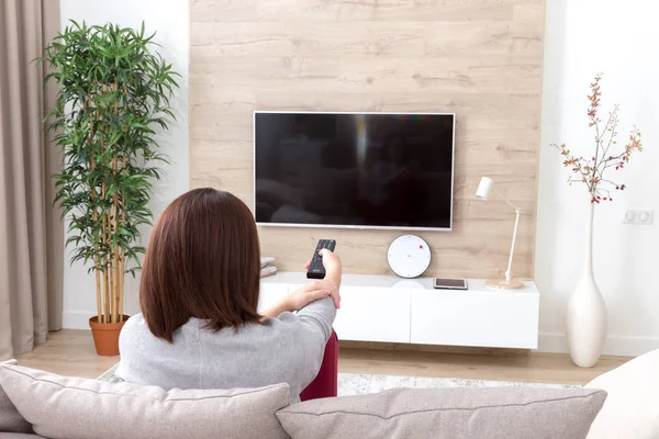 Mujer joven viendo la televisión en la habitación —  Fotos de Stock