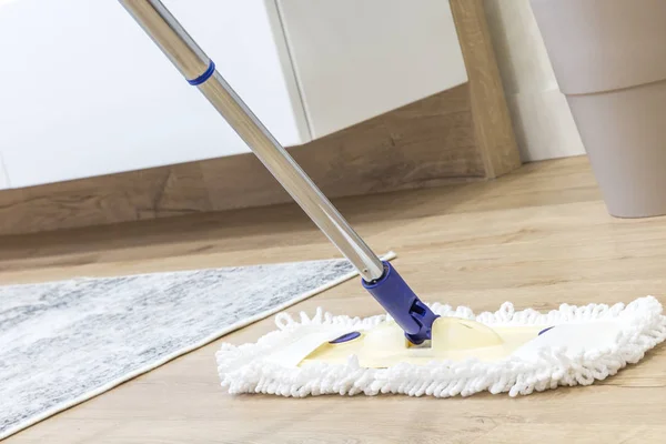 Modern white mop being used for cleaning a wooden floor — Stock Photo, Image