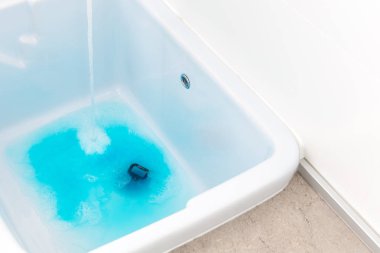 Çamaşır odasında çamaşır yıkamadan önce boş lavaboya mavi deterjan dökme