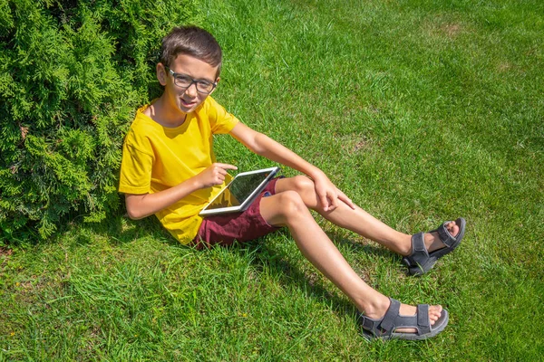 Cute boy playing internet games with tablet on a sunny day