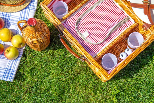 Conceito de piquenique com cesta no gramado ensolarado verde no parque — Fotografia de Stock