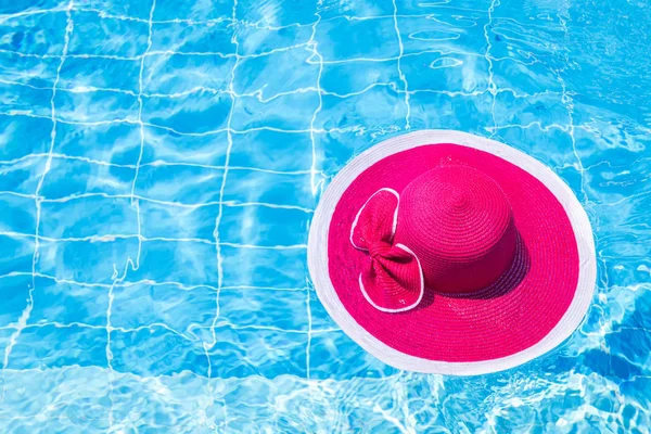 Nice pink hat with bow on water surface in swimming pool — Stock Photo, Image