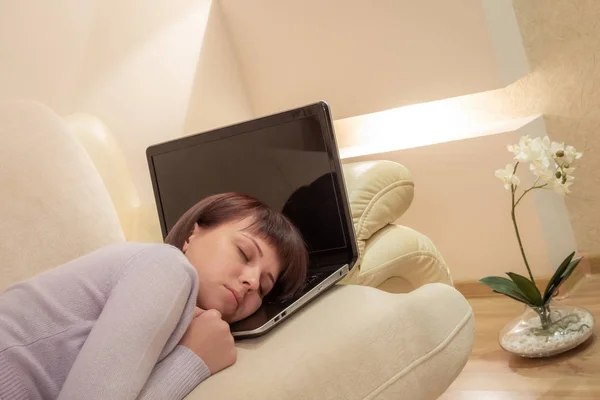 Trött kvinna sova på hennes laptop tangentbord på en soffa — Stockfoto