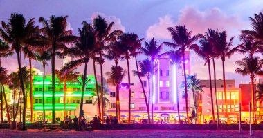 Gün batımında Miami Beach Ocean Drive otel ve restoranları. Geceleri palmiye ağaçları ile şehir silueti. Güney sahilinde Art deco gece hayatı