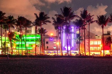Gün batımında Miami Beach Ocean Drive otel ve restoranları. Geceleri palmiye ağaçları ile şehir silueti. Güney sahilinde Art deco gece hayatı
