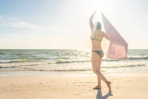 Frau mit Handtuch am Strand mit Ozean im Hintergrund — Stockfoto