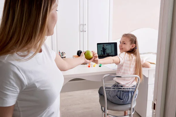 Moeder kijken naar haar dochter doet huiswerk op laptop thuis invoeren kamer en het geven van groene appel — Stockfoto