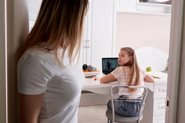 Anne, kızını evde dizüstü bilgisayarla ödev yaparken izliyor. — Stok fotoğraf