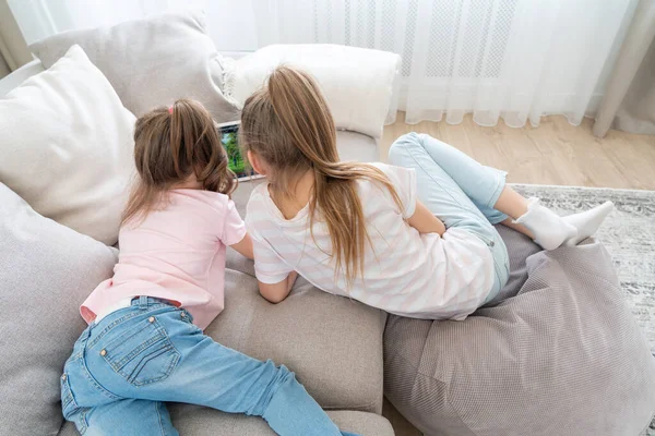 Zwei Schwestern liegen auf Couch und benutzen Tablet, Draufsicht — Stockfoto