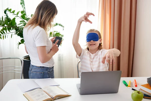 Anne genç kızın klavyede dokunmayı öğrenmesine yardım ediyor, kız uyku maskesi takmış gözleri kapalı daktilo yazıyor. — Stok fotoğraf