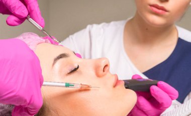 İki kozmetikçi aynı anda bir hastanın yüzüyle çalışıyor.