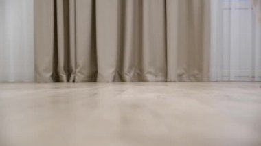 Genç bir kadın evdeki sıcak ahşap zeminde yalın ayak yürüyor, ağır çekim.