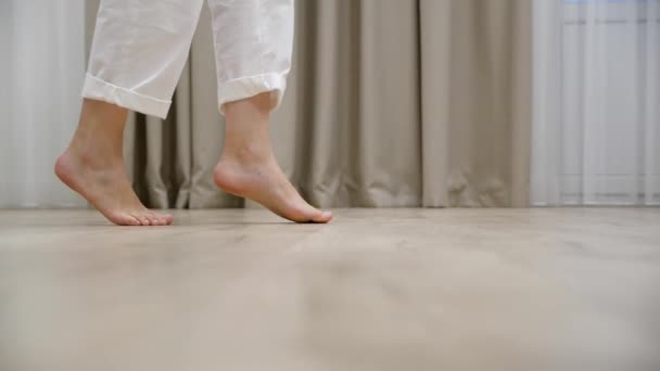 Jonge vrouw met haar dochter lopen tenen blootsvoets op een warme houten vloer thuis — Stockvideo