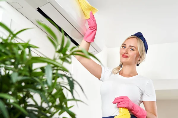 Mujer limpiando aire acondicionado con trapo. Servicio de limpieza o concepto de ama de casa — Foto de Stock