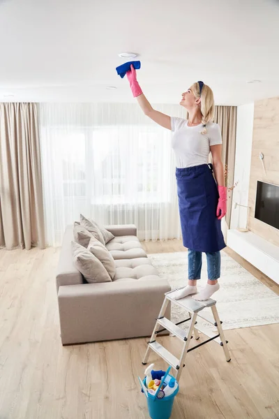 Mucama sosteniendo pila de trapeador, techo de limpieza en la sala de estar. Casa concepto de servicio de limpieza. — Foto de Stock