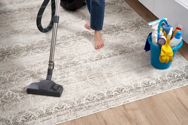 Жінка чистить килим за допомогою пилососа у вітальні — стокове фото