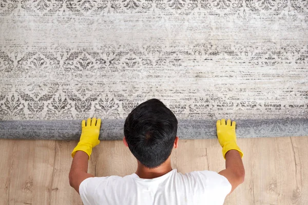 Vista de ángulo alto del hombre desenrollando la alfombra. Servicio de limpieza concepto —  Fotos de Stock