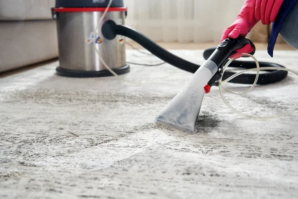 Menselijke schoonmaak tapijt in de woonkamer met behulp van Stofzuiger thuis — Stockfoto