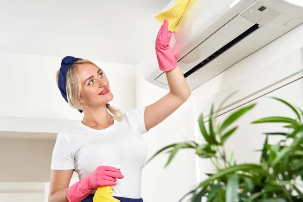 Woman cleaning air conditioner with rag. Cleaning service or housewife concept — Stock Photo, Image