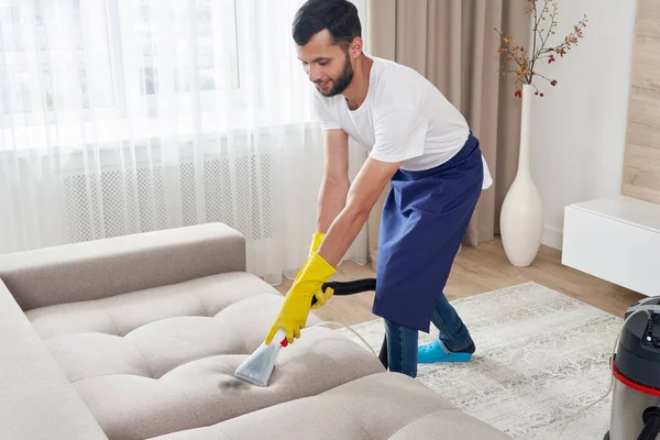 Close-up of housekeeper holding modern washing vacuum cleaner and cleaning dirty sofa with professionally detergent. Professional springclean at home concept — Stock Photo, Image