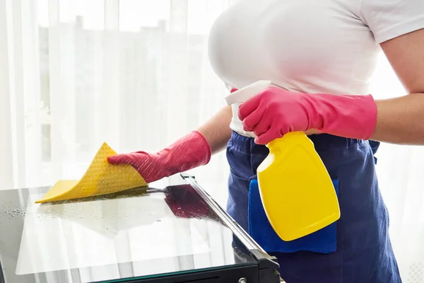 Молода жінка в рукавичках прибирає піч на кухні. Концепція клінінгової служби — стокове фото