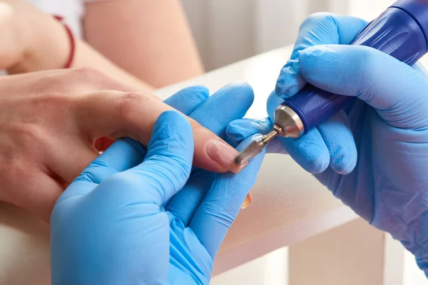 Manicure master uses an electric nail machine to remove nail polish hands in nail salon — Stock Photo, Image