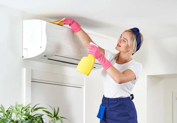 Kobieta czyści klimatyzator szmatą. Usługi sprzątania lub koncepcja gospodyni domowej — Zdjęcie stockowe