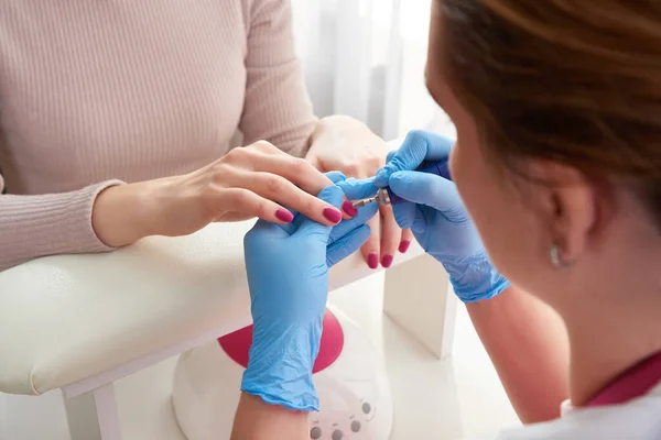 Manicura Master utiliza una máquina de uñas eléctrica para eliminar las manos de esmalte de uñas en el salón de uñas — Foto de Stock