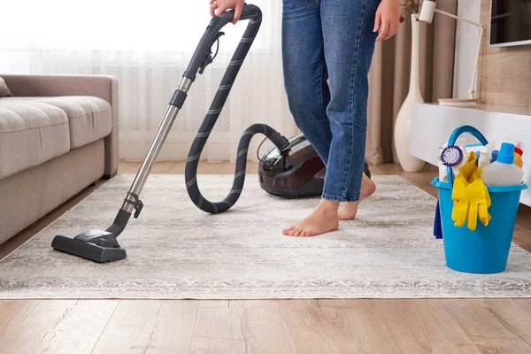 Mujer limpiando la alfombra con aspiradora en la sala de estar — Foto de Stock